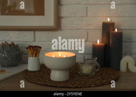 Bougies allumées et décor sur la table près du mur de briques blanches Banque D'Images