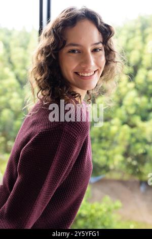 Femme souriante dans un pull confortable profitant du temps de détente à la maison Banque D'Images