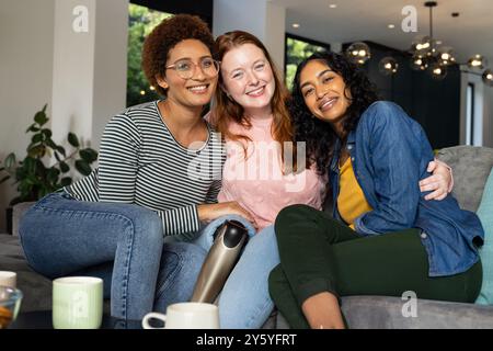 Souriant diverses femmes amis assis sur le canapé, appréciant le café et passant du temps ensemble Banque D'Images