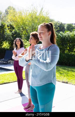 Pratiquer le yoga en plein air, diverses amies de femmes méditant sur des tapis de yoga ensemble Banque D'Images