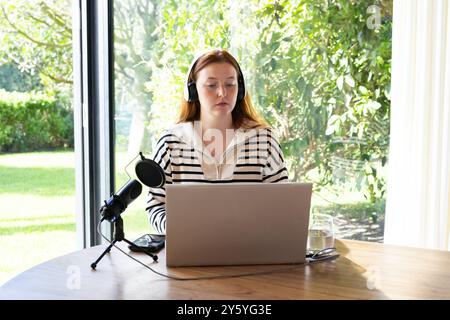 À l'aide d'un ordinateur portable et d'un microphone, femme enregistrant un podcast au bureau à domicile Banque D'Images