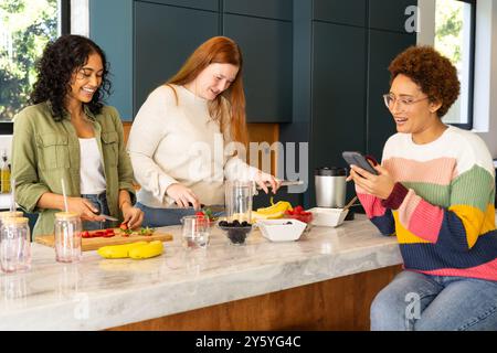 Préparer des fruits et des smoothies, des amis divers profitant du temps ensemble dans la cuisine Banque D'Images