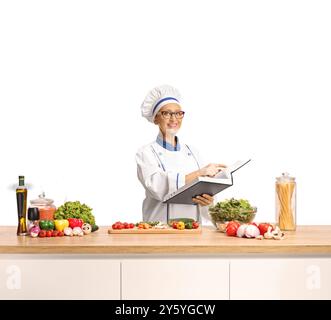 Femme chef lisant une recette dans un livre de cuisine et préparant un repas isolé sur fond blanc Banque D'Images
