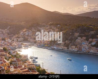 Île de Symi, Grèce - 20 avril 2023 : vue sur la baie principale de l'île de Symi, où s'amarrent les ferries touristiques et les yachts, qui étonne les visiteurs avec une atmosphère calme Banque D'Images