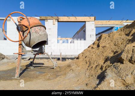 Malaxeur de ciment sur un chantier de construction avec mur partiellement construit Banque D'Images