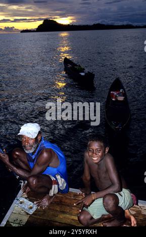 Pêcheur et jeune garçon du village au coucher du soleil, Îles Salomon Banque D'Images