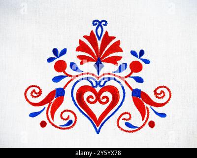 Ornement traditionnel slovène de broderie de nappe dans des couleurs bleues et rouges avec fleur d'oeillet et un coeur Banque D'Images