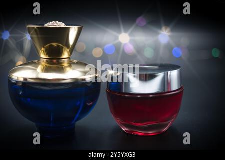 une bouteille de parfum sur un fond noir illuminé de lumières colorées Banque D'Images
