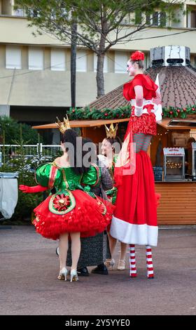 Une échassière et d'autres personnages costumés accueillent les touristes au marché de Noël de Port Hercule, Monte Carlo, Principauté de Monaco Banque D'Images