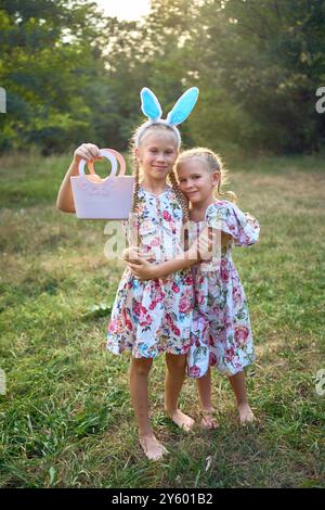 Deux petites filles s'embrassent et jouent aux lapins lors d'une chasse aux œufs de Pâques Banque D'Images