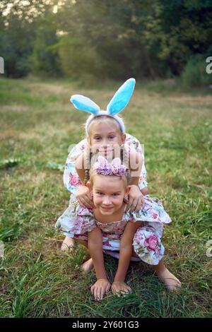 Deux petites filles s'embrassent et jouent aux lapins lors d'une chasse aux œufs de Pâques Banque D'Images