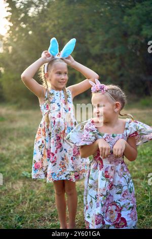 Deux petites filles s'embrassent et jouent aux lapins lors d'une chasse aux œufs de Pâques Banque D'Images