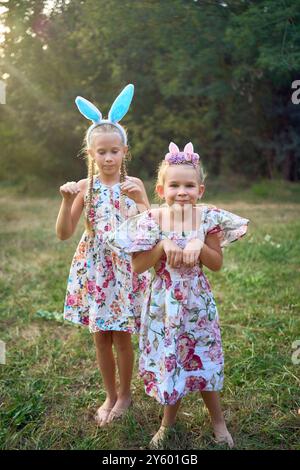 Deux petites filles s'embrassent et jouent aux lapins lors d'une chasse aux œufs de Pâques Banque D'Images