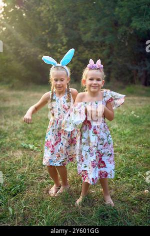 Deux petites filles s'embrassent et jouent aux lapins lors d'une chasse aux œufs de Pâques Banque D'Images