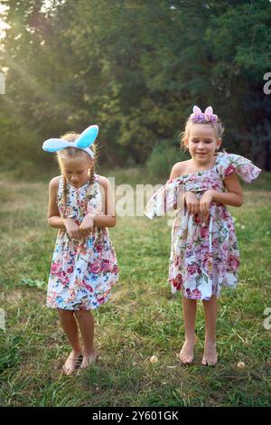 Deux petites filles s'embrassent et jouent aux lapins lors d'une chasse aux œufs de Pâques Banque D'Images