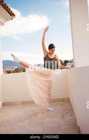 Une danse gracieuse pose sur un balcon avec une vue panoramique époustouflante sur le paysage environnant Banque D'Images