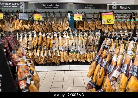 Une gamme de jambons ibériques en vente dans un supermarché en Espagne. Jamón ibérico, cuisse de variétés de porc. Accroché dans un magasin. Présentoir de cuisse de porc séchée en solde Banque D'Images