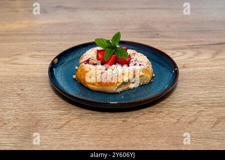 Gâteau à la levure fait à la main avec des fraises et du pudding, couché sur une plaque bleue. Banque D'Images