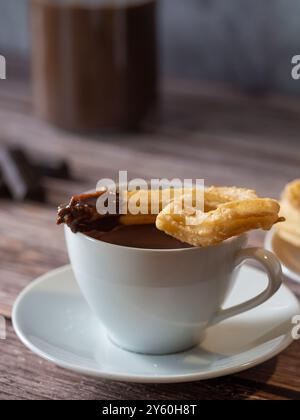 gros plan d'un churro recouvert de chocolat sur une tasse blanche de chocolat chaud Banque D'Images