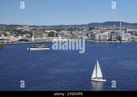 Vue côtière urbaine avec un voilier, port moderne et bâtiments environnants, ferry électrique, capitale, Oslo, Norvège, Europe Banque D'Images