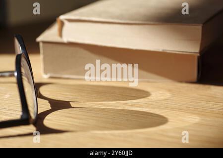 Lecture d'image symbolique, lunettes, ombre, verre, livres, lecture, réflexion, à la lumière du soleil, les ombres de lunettes tombent sur un plateau de table. Deux livres Banque D'Images