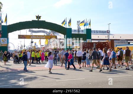 Munich, Bavière, Allemagne - 23 septembre 2024 : les visiteurs traversent l'entrée principale de l'Oktoberfest, qui est décorée du Münchner Kindl et de l'arc typique Bienvenue à l'Oktoberfest *** Besucher strömen durch den Haupteingang des Oktoberfest, der mit dem Münchner Kindl und dem typischen Willkommen zum Oktoberfest-Bogen geschmückt ist Banque D'Images