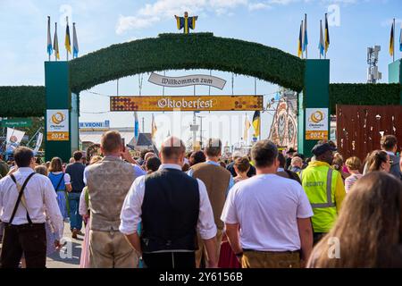 Munich, Bavière, Allemagne - 23 septembre 2024 : les visiteurs traversent l'entrée principale de l'Oktoberfest, qui est décorée du Münchner Kindl et de l'arc typique Bienvenue à l'Oktoberfest *** Besucher strömen durch den Haupteingang des Oktoberfest, der mit dem Münchner Kindl und dem typischen Willkommen zum Oktoberfest-Bogen geschmückt ist Banque D'Images