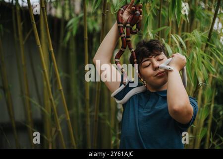 Fille interagissant avec des serpents colorés dans un cadre de forêt de bambou Banque D'Images