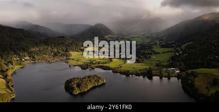 Paysage panoramique aérien du village et du lac de Grasmere dans le parc national du Lake District avec l'eau calme et le soleil dans la vallée et un bro Banque D'Images