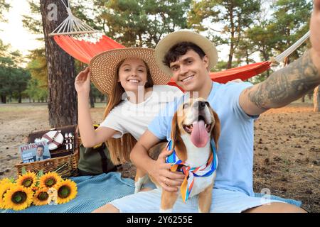 Jeune couple avec chien Beagle prenant selfie sur pique-nique dans la forêt Banque D'Images