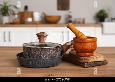 Casserole, poêle, mortier et pilon sur le comptoir en bois dans la cuisine Banque D'Images