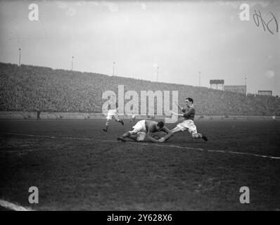 Hesford, gardien de but pour Huddersfield Town, et K. Armstron, attaquant central pour Chelsea (chemise bleue) s’emmêlent alors qu’ils vont tous les deux pour le ballon lors de la rencontre entre les deux clubs à Stamford Bridge, aujourd’hui. 17 janvier 1948 Banque D'Images