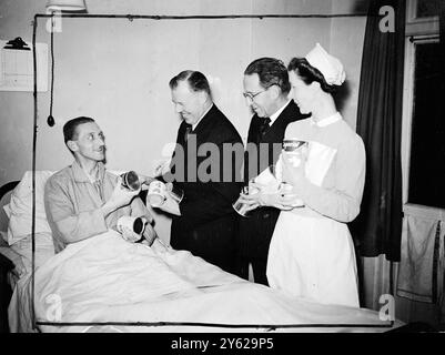 Au Metropolitan police Nursing Home, Grove Park, cet après-midi, des colis de fruits envoyés par des policiers de Nouvelle-Galles du Sud ont été distribués au policier londonien convalescent par M. Harry Simpson, directeur général du New South Wales Food from Britain Appeal Fund. Images : L'inspecteur W.J.Lewis de Chertsey, convalescent à la maison, reçoit des fruits en conserve australiens de M. Harry Simpson. À côté de M. Simpson se trouvent Sir Harold Scott, KCB, KBE, commissaire de police et de la métropole et sœur Margaret H. Marrison. 28 novembre 1947 Banque D'Images