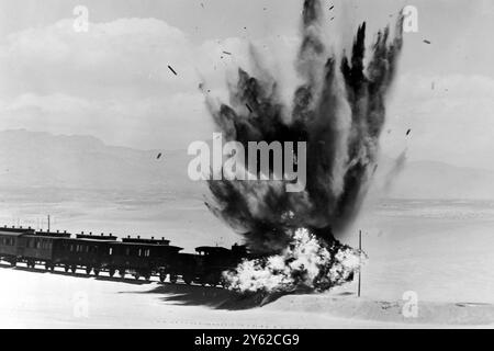 LE TRAIN DE PASSAGERS A EXPLOSÉ ? Almeria, Espagne : Un train de voyageurs à vitesse excessive, composé d'une locomotive, de huit voitures de voyageurs, de deux fourgonnettes de fret et d'un fourgon de garde, et d'un poids total de deux cent trois tonnes, sont soufflés hors de la piste pour une séquence dans le film Lawrence d'Arabie, maintenant sur place en Espagne. Dix livres de coton canon et dix livres de poudre à canon ont été utilisées pour déclencher l'explosion qui a entassé le train. Cinq caméras cinématographiques, dont trois bunkers ensachés de sable, ont filmé la séquence un seul plan. Le train utilisé pour le tir a été acheté aux chemins de fer espagnols. 18 JUIN 1962 Banque D'Images