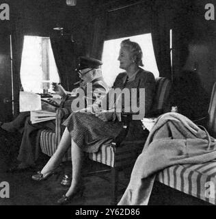 À bord du train spécial du premier ministre lors d'un voyage à travers le Canada et les États-Unis : Mr. Churchill Reading dépêches, avec Mme Churchill. Pour son voyage au Canada et aux États-Unis d'Amérique, le premier ministre a utilisé un train spécial que lui et ses secrétaires ont pu travailler en voyageant. Cette excellente étude de notre grand premier ministre et de sa femme lui montre -inévitable cigare dans la bouche-lecture de dépêches importantes. 2 octobre 1943 Banque D'Images