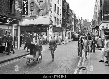 Le centre de la mode londonien pour les plus jeunes est Carnaby Street, la rue la plus connue, sinon la plus populaire de Londres. Les jeunes aux cheveux longs parlent loin les heures à Carnaby Street la Mecque des modes mod de la capitale anglaise tout ce qui va de la mini-jupes aux derniers styles de vestes et pantalons pour hommes peut être acheté à Carnaby Street, le siège de la mode des jeunes 20 juillet 1967 Banque D'Images