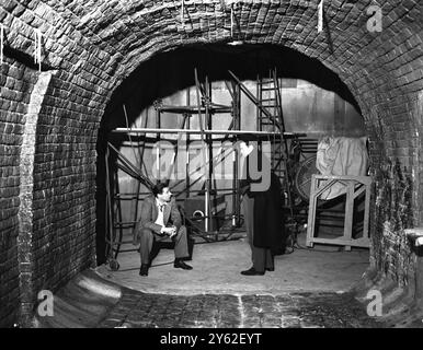 La réalisatrice britannique , Carol Reed , ( assis ) parle à l'acteur américain , Orson Welles , de la maquette des égouts viennois pendant le tournage de , le troisième homme . L'histoire et le scénario sont du romancier anglais Graham Greene sorti en 1949 Banque D'Images