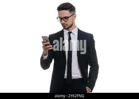 Discussion rapide avec un partenaire commercial. Jeune homme sérieux en costume complet tapant un message texte à l'aide de son téléphone intelligent tout en se tenant debout sur fond blanc Banque D'Images