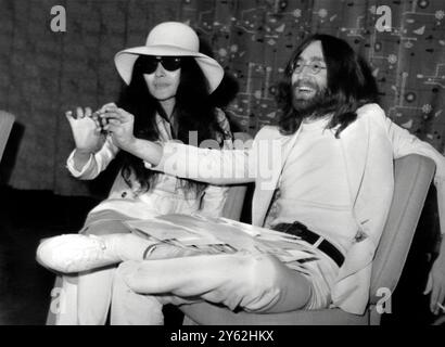 Beatle John Lennon et sa femme Yoko Ono après leur arrivée à l'aéroport de Londres Heathrow. Ils étaient restés au lit pendant une semaine à l'hôtel Hilton d'Amsterdam pour protester contre la violence dans le monde. Ils tiennent chacun un petit gland qu'ils ont annoncé qu'ils envoyaient à chacun des dirigeants du monde, pour leur demander de les planter pour la paix. 1er avril 1969 Banque D'Images