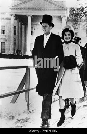 Le président John Kennedy et Mme Jacqueline Kennedy marchent le long d'une plate-forme sur leur chemin vers le stand d'examen pour assister à la parade inaugurale . En arrière-plan est leur nouvelle maison, la célèbre Maison Blanche . 20 janvier 2961 Banque D'Images