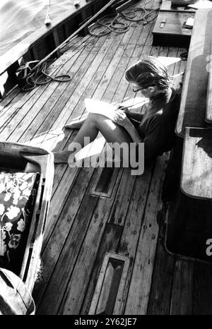 Une jeune femme prend le temps d'un séjour de voile relaxant pour s'asseoir sur le pont et écrire une lettre à un ami le 1er septembre 1965 Banque D'Images