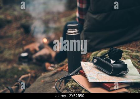 Le temps de se reposer après une longue route. Gros plan vue arrière d'un jeune homme se réchauffant près du feu de camp alors qu'il était assis dans la forêt Banque D'Images