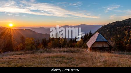 Belle vue sur la petite cabane en bois et le lac Zaovine pendant le coucher du soleil au point de vue Zmajevac, montagne Tara, Serbie. Banque D'Images