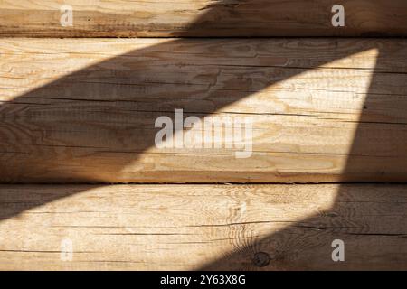 Mur en bois fait de bûches de pin taillées naturelles non colorées avec motif d'ombre, vue frontale, texture de photo de fond. La maison en rondins est en construction Banque D'Images