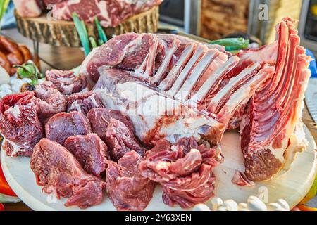 Une variété de coupes de viande crue, y compris des côtes levées et du filet, présentées sur une planche de bois, prêtes pour la préparation et la cuisson Banque D'Images