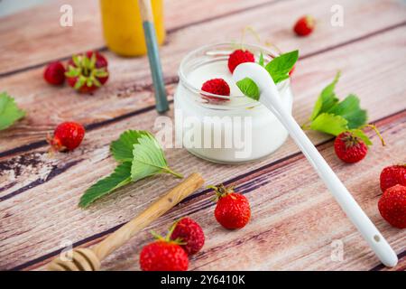 yaourt sucré maison dans un pot avec des fraises, sur une table en bois. Banque D'Images