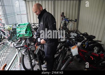 Le sergent Chris Hook s'occupe de vélos électriques illégalement modifiés confisqués au poste de police de Bishopsgate à Londres. Les saisies policières de vélos électriques illégalement modifiés (e-bikes) ont grimpé en flèche au cours de l'année écoulée, en raison de préoccupations concernant leur vitesse et leur poids, qui représentent une menace mortelle pour les piétons, selon les chiffres de Freedom of information (foi) obtenus par l'agence de presse PA. Les forces à travers le Royaume-Uni ont confisqué 937 vélos électriques dans l'année jusqu'au 11 août. Date de la photo : jeudi 12 septembre 2024. Banque D'Images