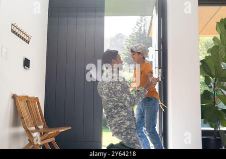 Accueil à la maison, jeune fils embrassant père indien en uniforme militaire à la porte d'entrée Banque D'Images