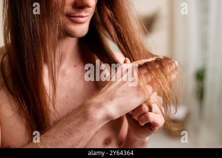 Concept de soins capillaires pour hommes. Jeune homme regardant ses cheveux, problèmes de cheveux chez les hommes, perte de cheveux Banque D'Images
