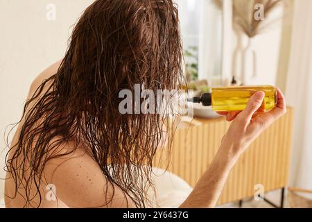 Homme avec les cheveux longs appliquant des huiles sur les cheveux mouillés dans un environnement confortable, soins capillaires, beau concept de cheveux Banque D'Images